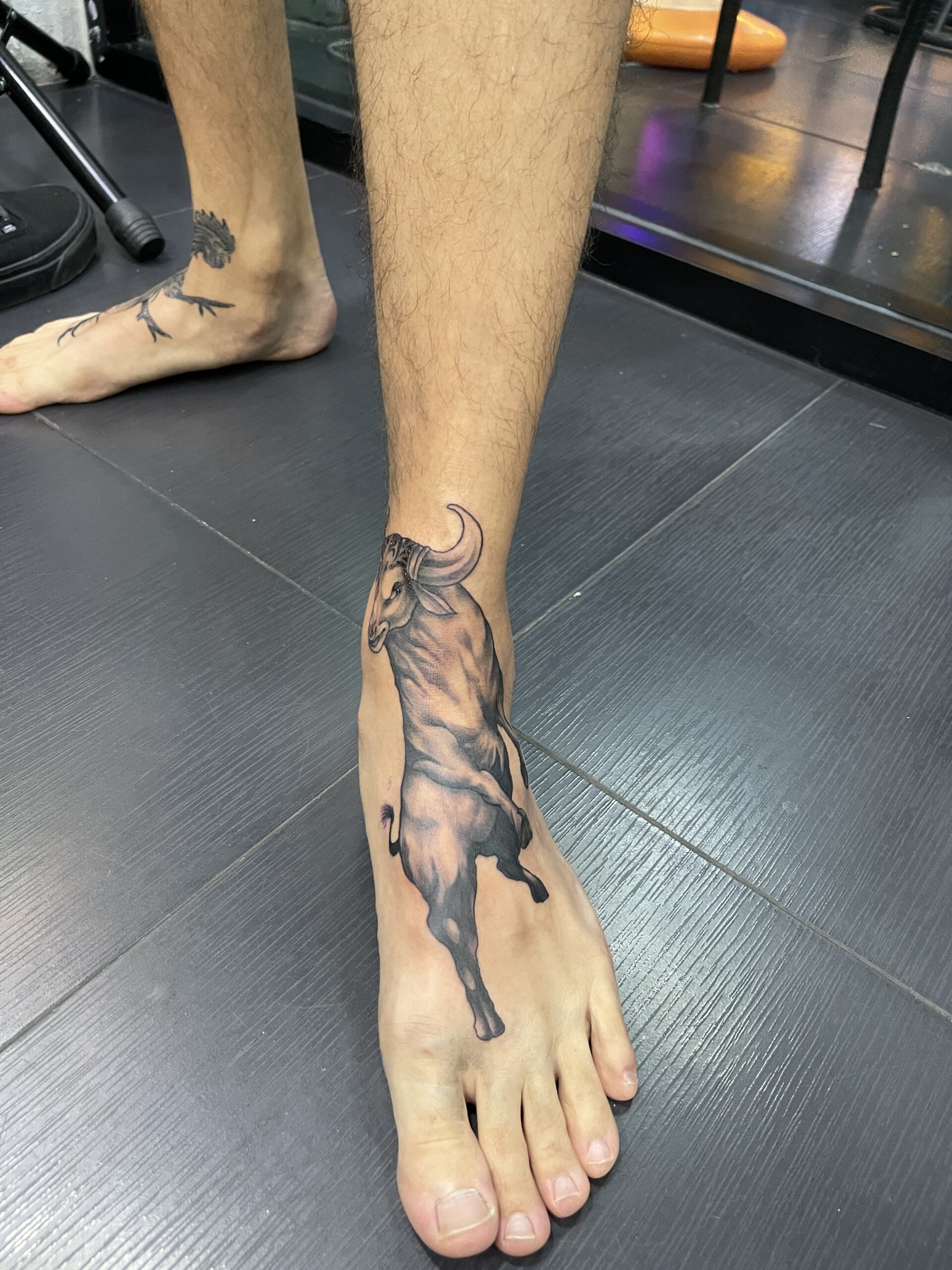 Black and grey, Bull, Foot Tattoo by Toon. He is a highly skilled tattoo artist at Lethal Ink Tattoo in Pattaya. He is celebrated for his expertise in Japanese, Chicano, Realistic, New School, Old School, Neo Thai, and Bamboo Tattooing. Toon, Black and grey, Bull, Foot Tattoo, Lethal Ink, Pattaya, 2024
