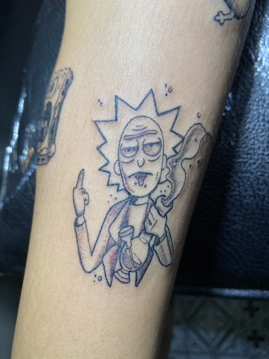 Rick, Scientist, Cartoon Black tattoo by Max. He is a highly skilled tattoo artist at Lethal Ink Tattoo in Pattaya. He is celebrated for is expertise in black and grey, anime, manga, Thai art, and tribal motifs. Rick, Scientist, Cartoon Black Tattoo, Max, Lethal Ink, Pattaya, 2024