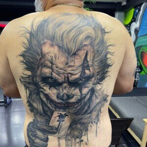 Black and grey, Joker, Back Tattoo by Max. He is a highly skilled tattoo artist at Lethal Ink Tattoo in Pattaya. He is celebrated for his expertise in black and grey, anime, manga, Thai art, and tribal motifs. Max, black and grey, Joker, Back Tattoo, Lethal Ink, Pattaya, 2024