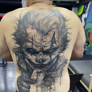 Black and grey, Joker, Back Tattoo by Max. He is a highly skilled tattoo artist at Lethal Ink Tattoo in Pattaya. He is celebrated for his expertise in black and grey, anime, manga, Thai art, and tribal motifs. Max, black and grey, Joker, Back Tattoo, Lethal Ink, Pattaya, 2024