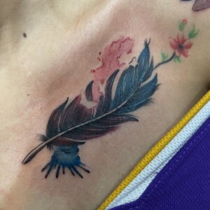 Feather, Flowers, Color, Chest tattoo by Max. He is a highly skilled tattoo artist at Lethal Ink Tattoo in Pattaya. He is celebrated for is expertise in black and grey, anime, manga, Thai art, and tribal motifs. Feather, Flowers, Color, Chest Tattoo, Max, Lethal Ink, Pattaya, 2024