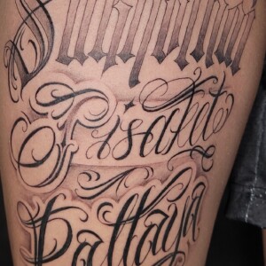 Black and grey Old English lettering tattoo on arm by Sandy at Lethal Ink Tattoo, Pattaya. Sandy specializes in Black and Grey, Lettering, Old English, Fine Line, and Script tattoos. Black and grey Old English lettering tattoo on arm by Sandy, tattoo artist at Lethal Ink Tattoo, Pattaya (2025)