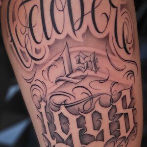Chicano black and grey tattoo on arm by Sandy at Lethal Ink Tattoo, Pattaya. Sandy specializes in Chicano, Black and Grey, Realism, Portrait, and Fine Line tattoos. Chicano black and grey tattoo on arm by Sandy, tattoo artist at Lethal Ink Tattoo, Pattaya (2025)