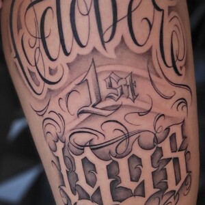 Chicano black and grey tattoo on arm by Sandy at Lethal Ink Tattoo, Pattaya. Sandy specializes in Chicano, Black and Grey, Realism, Portrait, and Fine Line tattoos. Chicano black and grey tattoo on arm by Sandy, tattoo artist at Lethal Ink Tattoo, Pattaya (2025)