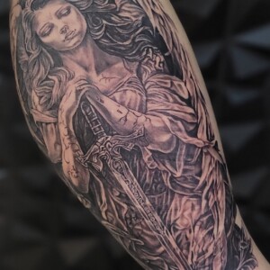 Black and grey guardian angel tattoo with sword by Sandy at Lethal Ink Tattoo, Pattaya. Sandy specializes in Realism, Illustrative, Black & Grey, Portrait, and Neo Traditional styles. Black and grey guardian angel tattoo with sword by Sandy, tattoo artist at Lethal Ink Tattoo, Pattaya (2025)