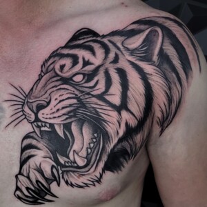 Black illustrative tiger head tattoo on chest by Sandy at Lethal Ink Tattoo, Pattaya. Sandy specializes in Illustrative, Blackwork, Realism, Neo Traditional, and Black & Grey styles. Black illustrative tiger head tattoo on chest by Sandy, tattoo artist at Lethal Ink Tattoo, Pattaya (2025)