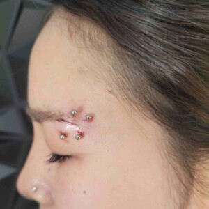 Piercing de ceja con forma de banana y extremo de bola en forma de estrella en el lado izquierdo en Lethal Ink Tattoo Pattaya. Piercing de ceja con segundo anillo y forma de banana, con extremo de bola en forma de estrella, en el lado izquierdo, realizado con acero quirúrgico en Lethal Ink Tattoo Pattaya (2026).