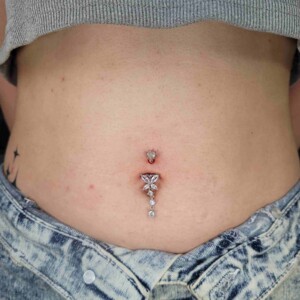 Piercing en el ombligo con gema en forma de mariposa en Lethal Ink Tattoo Pattaya. Piercing en el ombligo con gema transparente en forma de mariposa y barra de acero quirúrgico en forma de banana en Lethal Ink Tattoo Pattaya (2026)